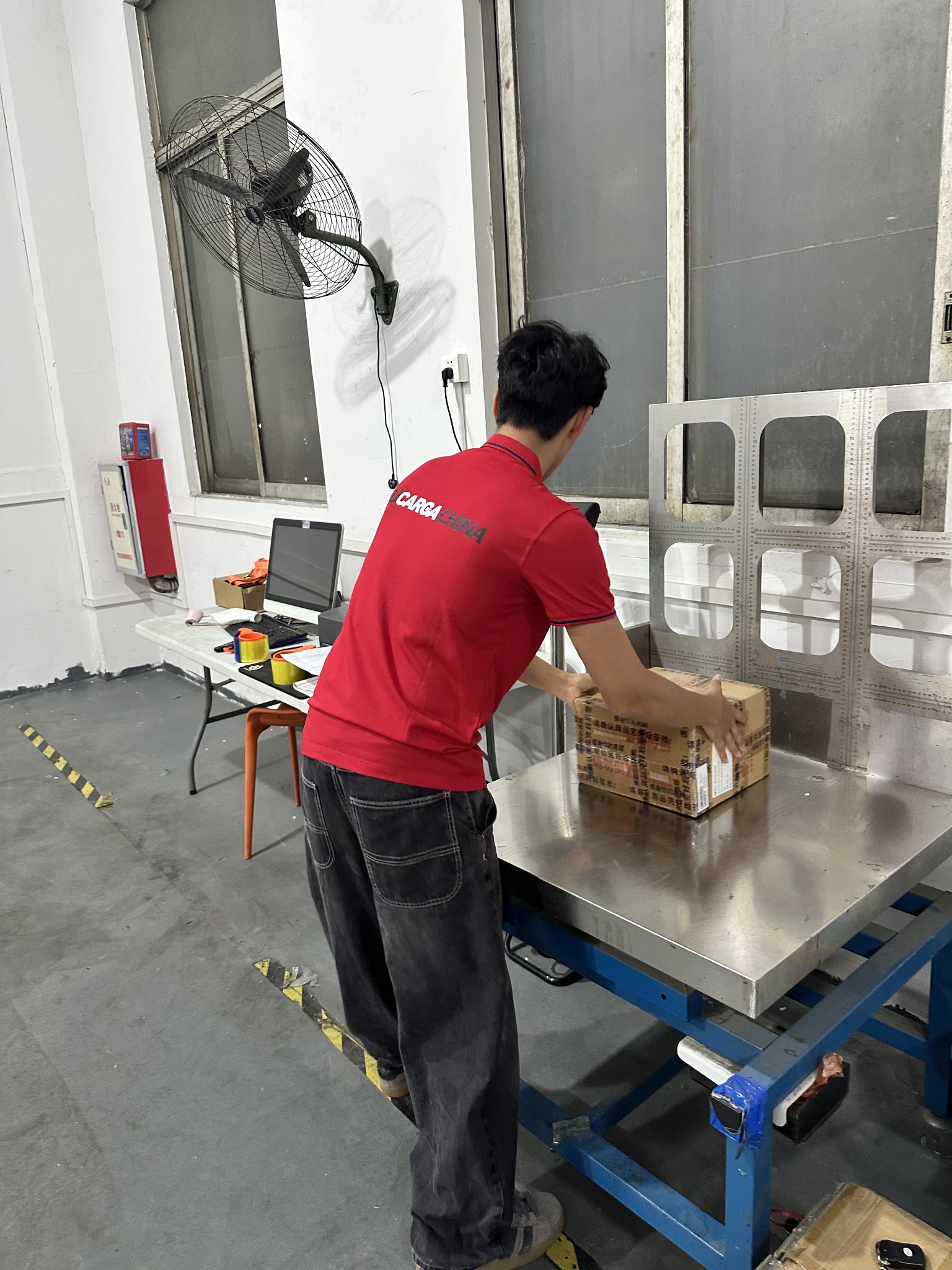 Colaborador de TUCARGACHINA colocando un paquete en una balanza de bodega