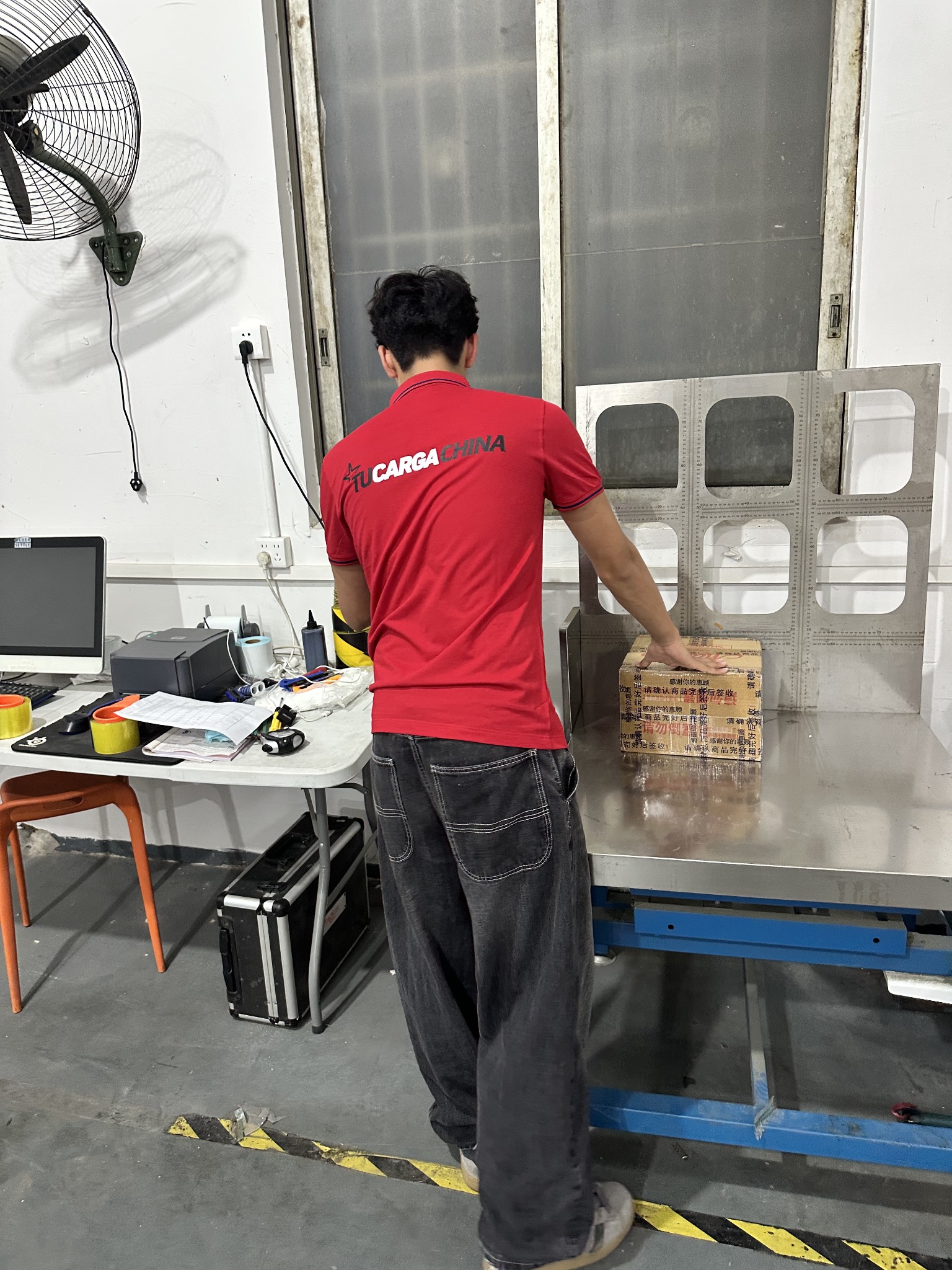 Colaborador de TUCARGACHINA colocando un paquete en una balanza de bodega